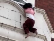 Una niña se aferra al alféizar de una ventana encima de una tienda de Londres momentos antes de caer sobre un hombre y un oficial de policía debajo.
